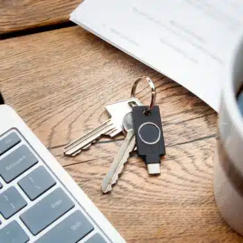 Yubikey C Bio accrochée en trousseau à côté d'une tasse de café