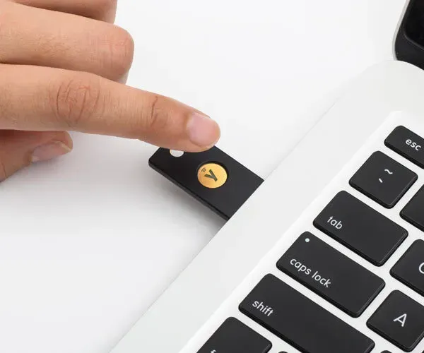 YubiKey 5 NFC FIPS 140-2 branchée sur le port USB-A d'un ordinateur portable, doigt sur le bouton tactile