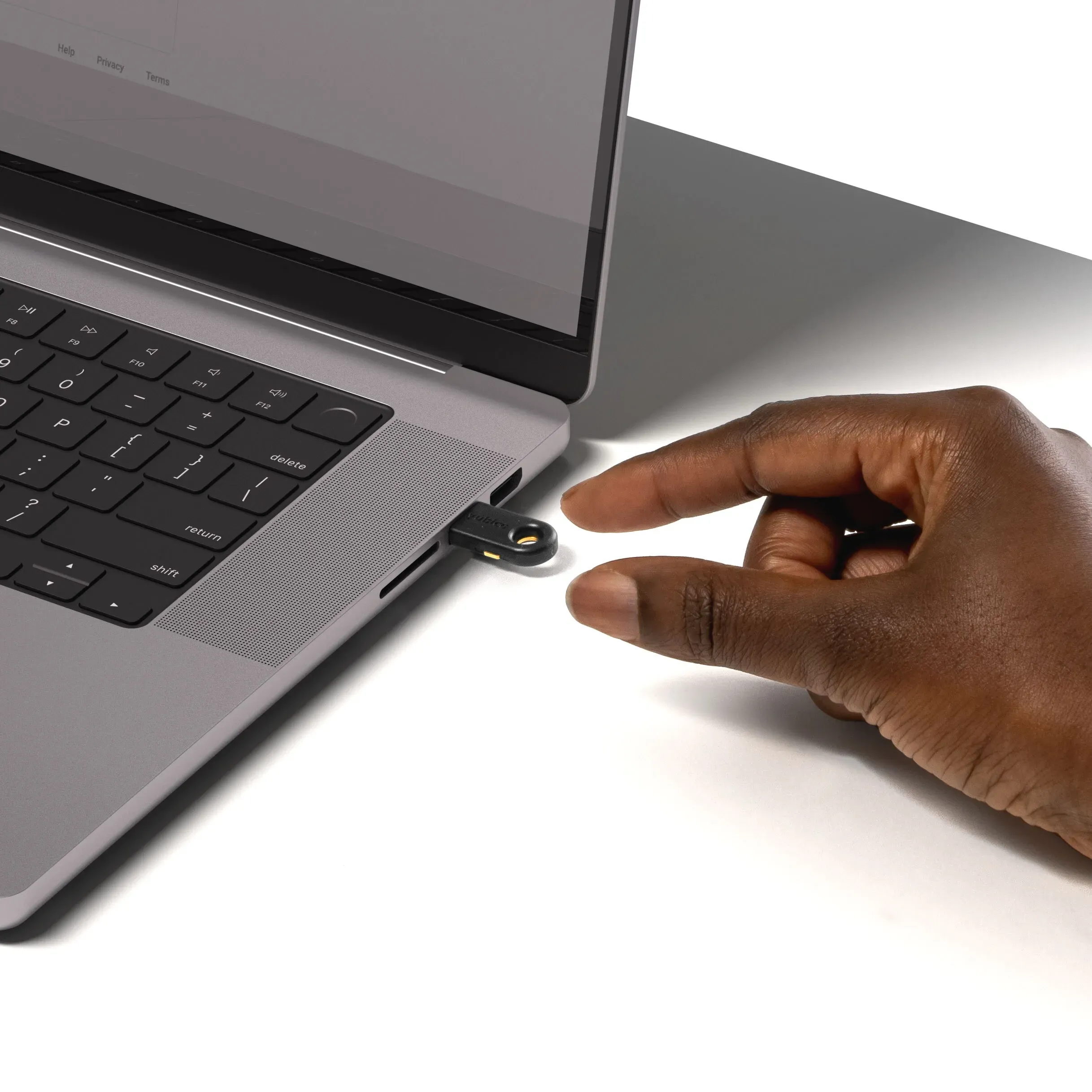 YubiKey 5C branchée sur le port USB-C d'un ordinateur portable, doigt sur le capteur tactile
