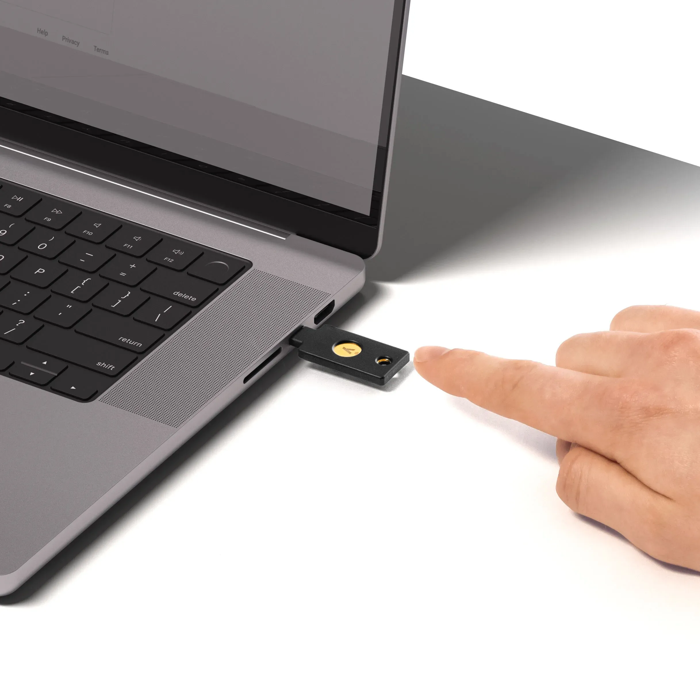 YubiKey 5C NFC FIPS 140-3 branchée sur le port USB-C d'un ordinateur portable, doigt sur le bouton tactile