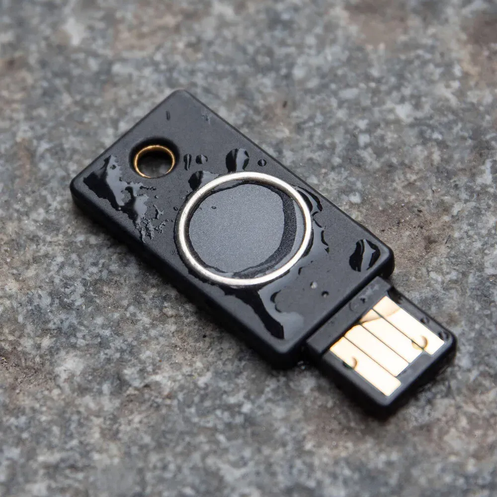 YubiKey Bio USB-A couverte de gouttes d'eau, posée sur une surface en pierre