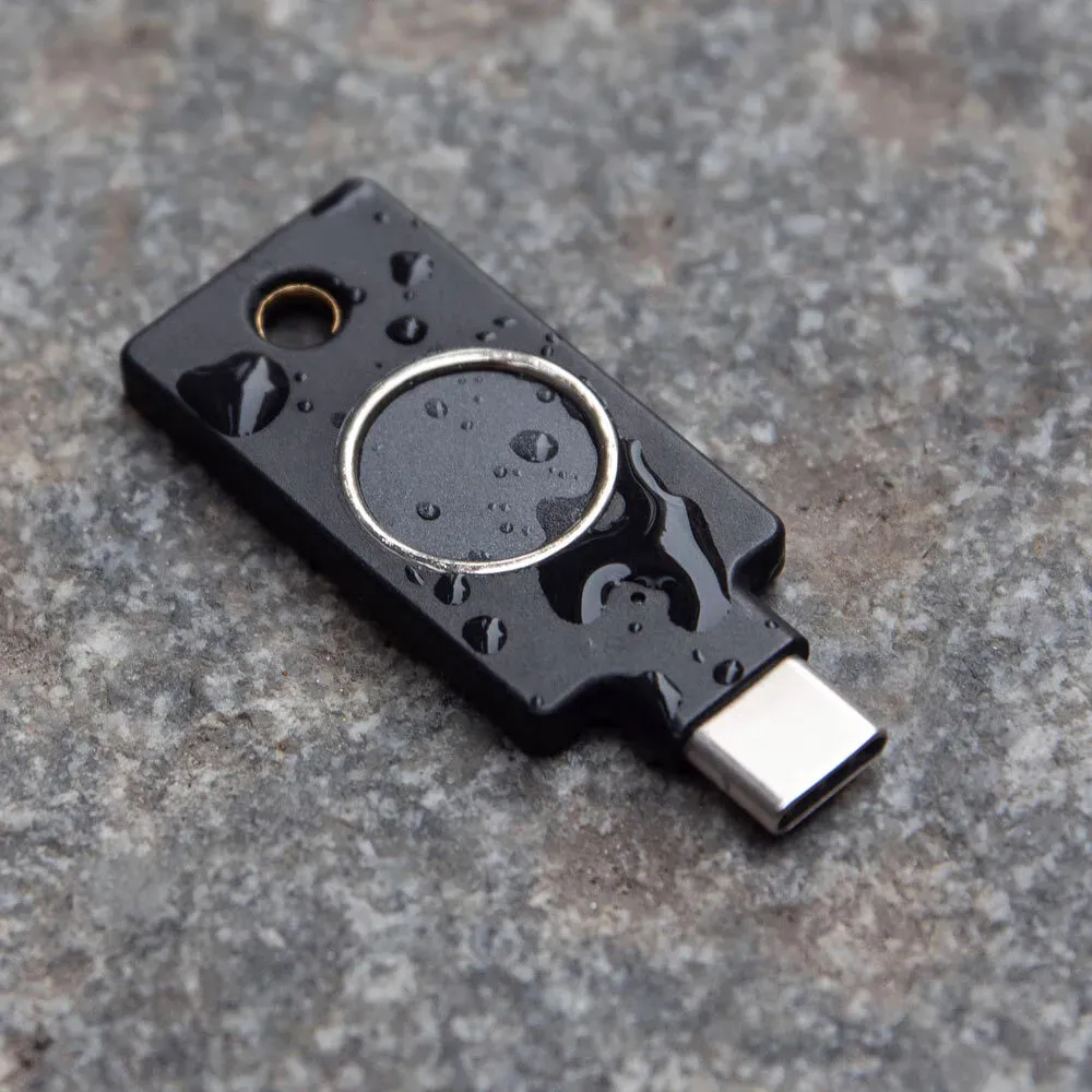 YubiKey C Bio USB-C couverte de gouttes d'eau, posée sur une surface en pierre